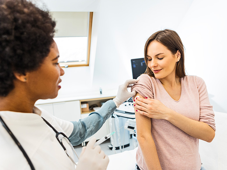 Doctor administering vaccine to pregnant patient.